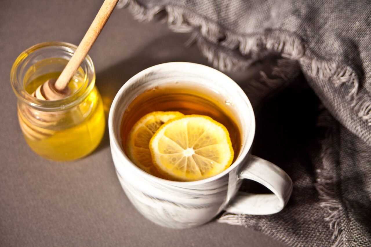 Tasse de grog maison chaud avec une rondelle de citron et une cuillère de miel.